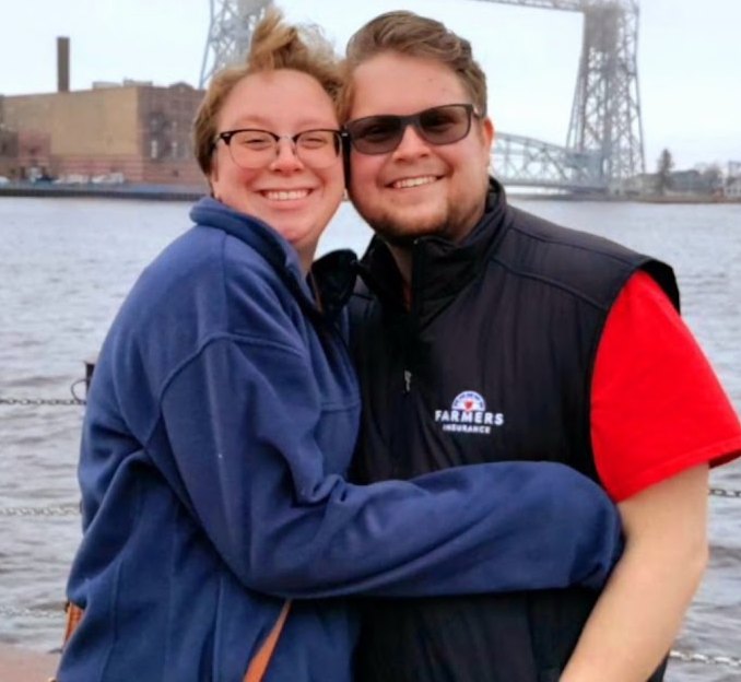 Kendra and Anthony smiling together by the water.